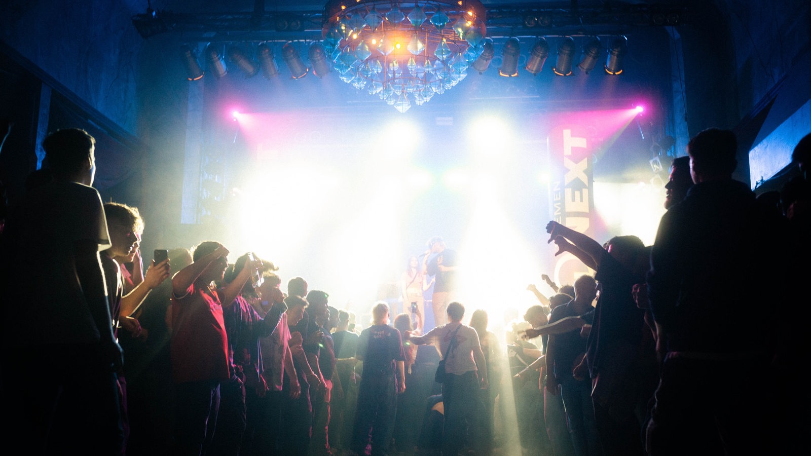 Publikum bildet ein Moshpit während Künstler auf der Bühne performt.