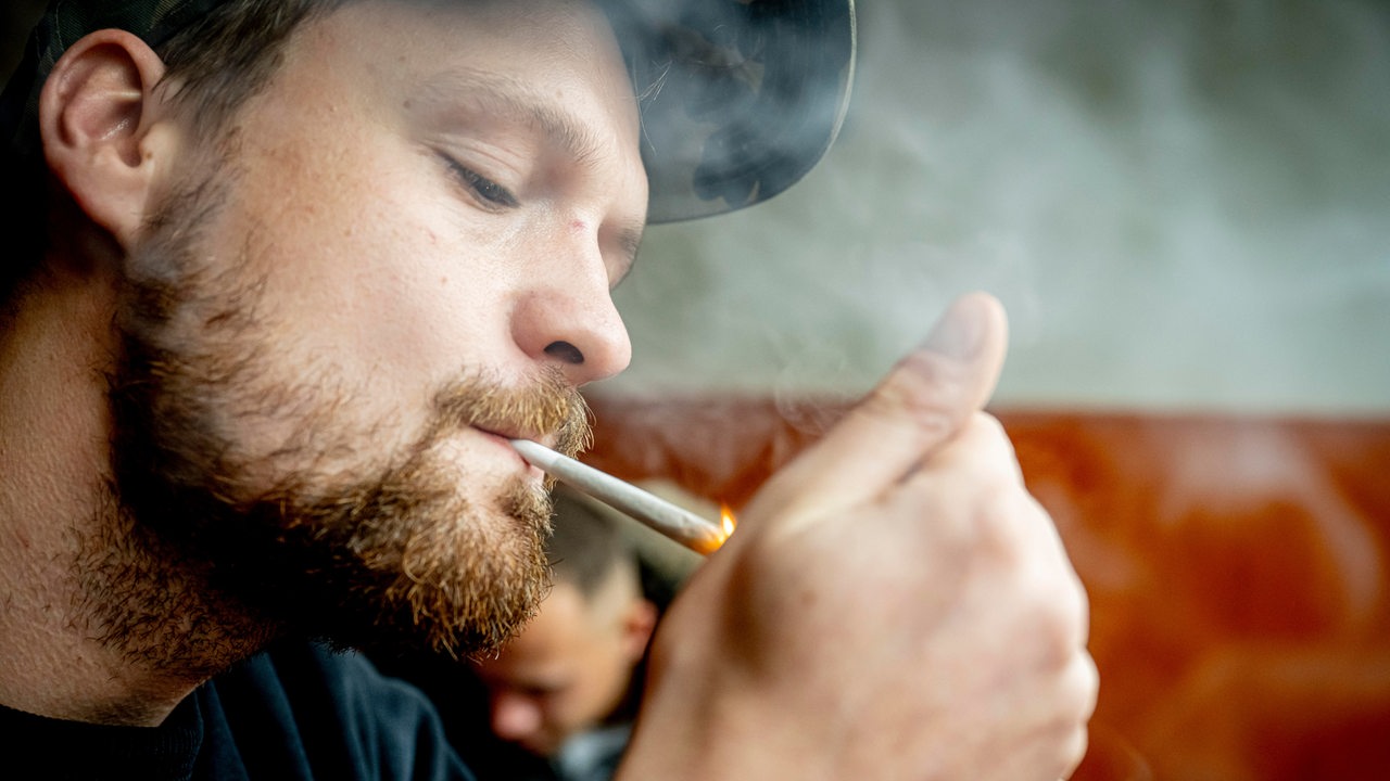 Ein junger Mann raucht einen Joint.