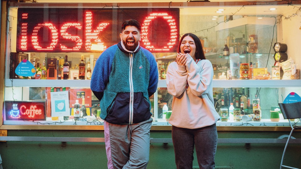 Meltem und Yousuf von Chai Society stehen vor einem Kiosk.