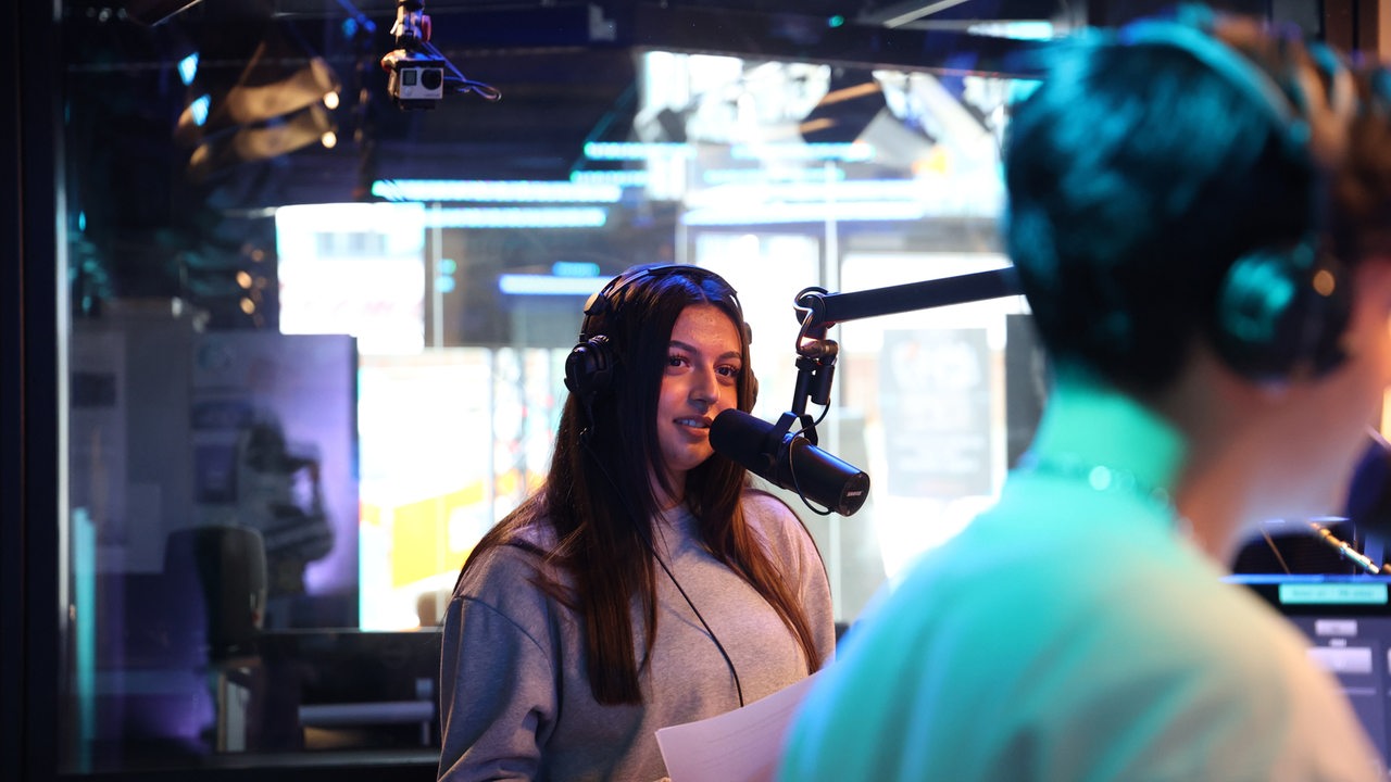 Eine Schülerin steht an einem Mikrofon im Studio
